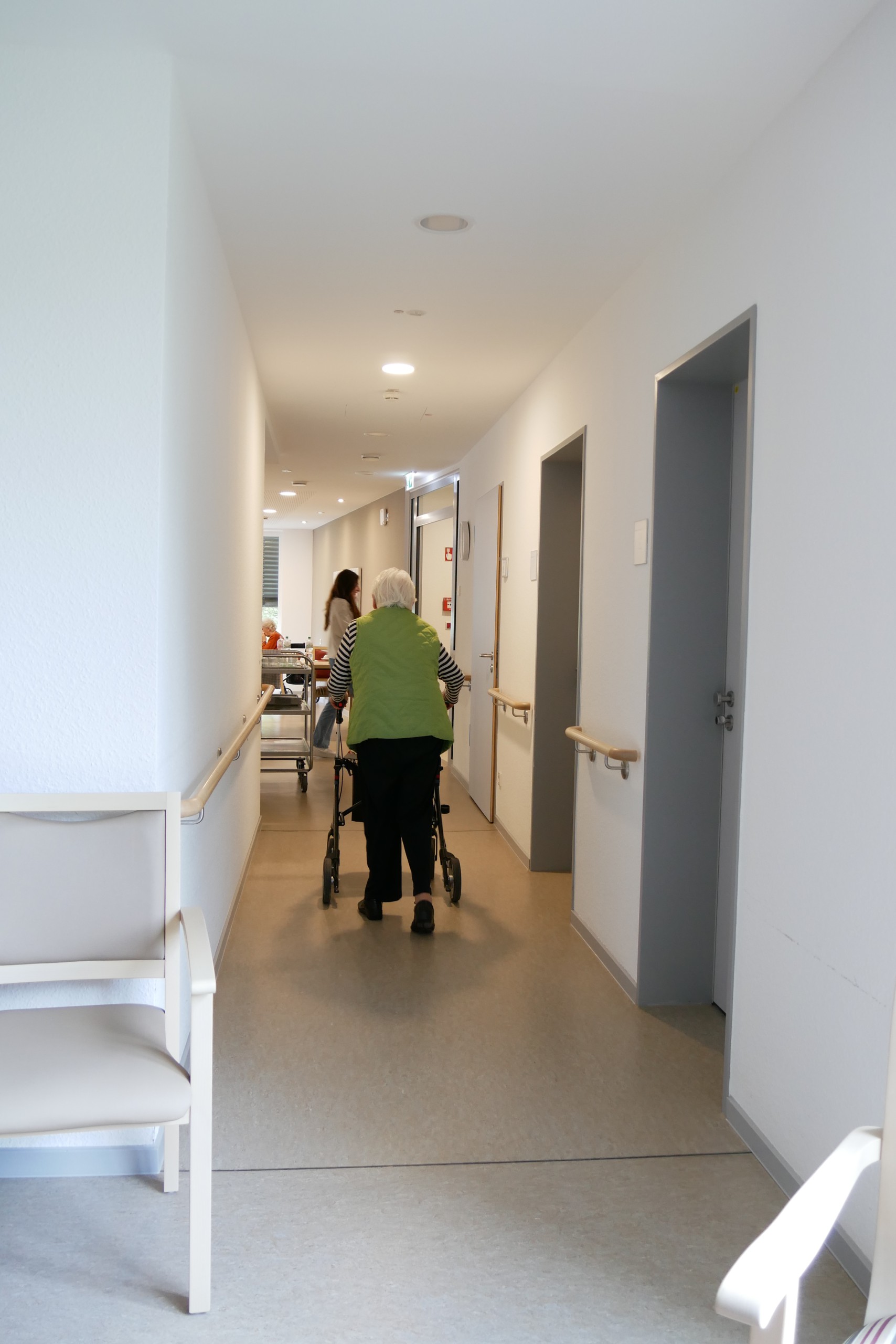 Eine Person geht mit einem Rollator den Flur entlang