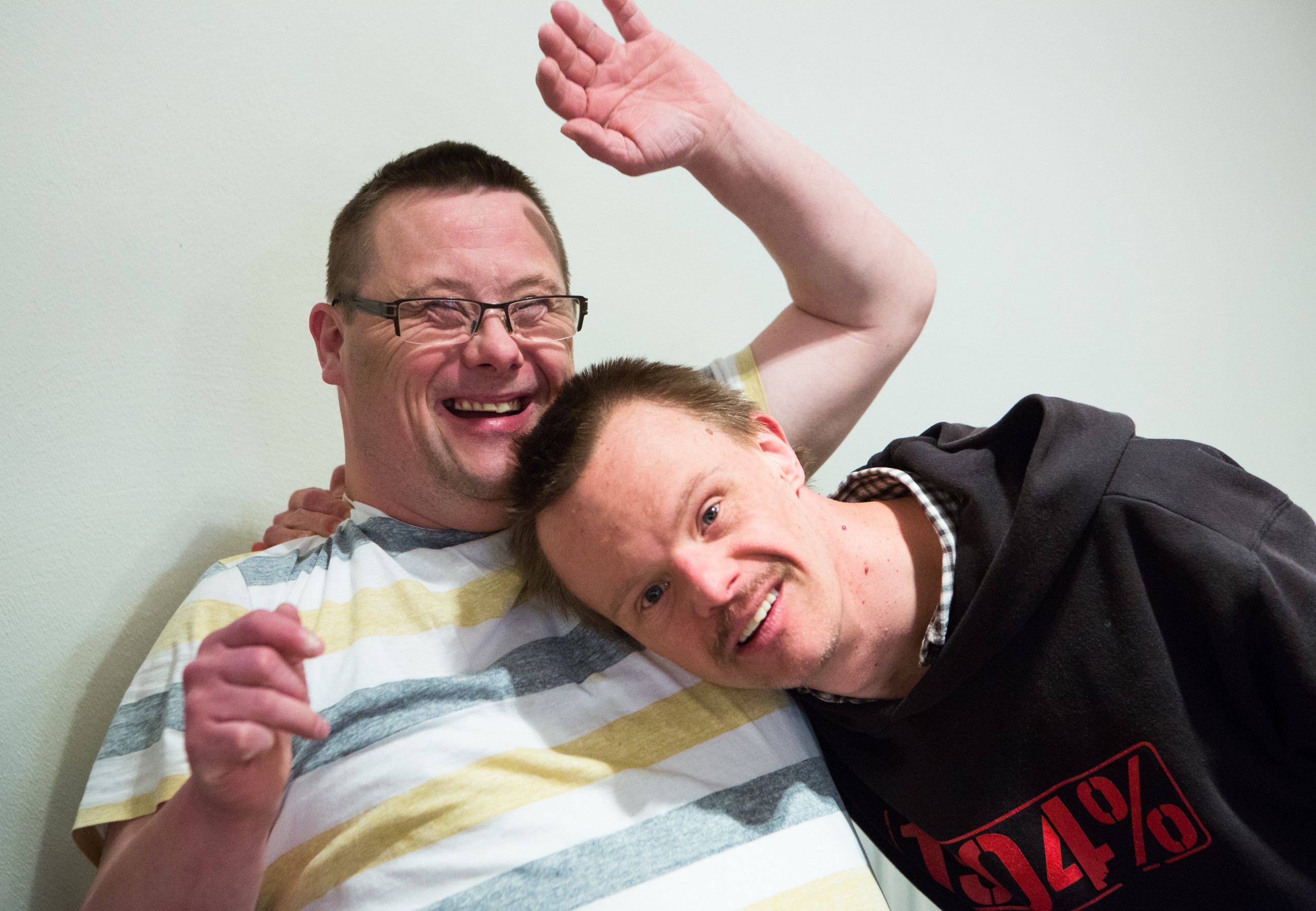 Zwei Menschen mit Behinderung lachen gemeinsam in freundschaftlicher Pose