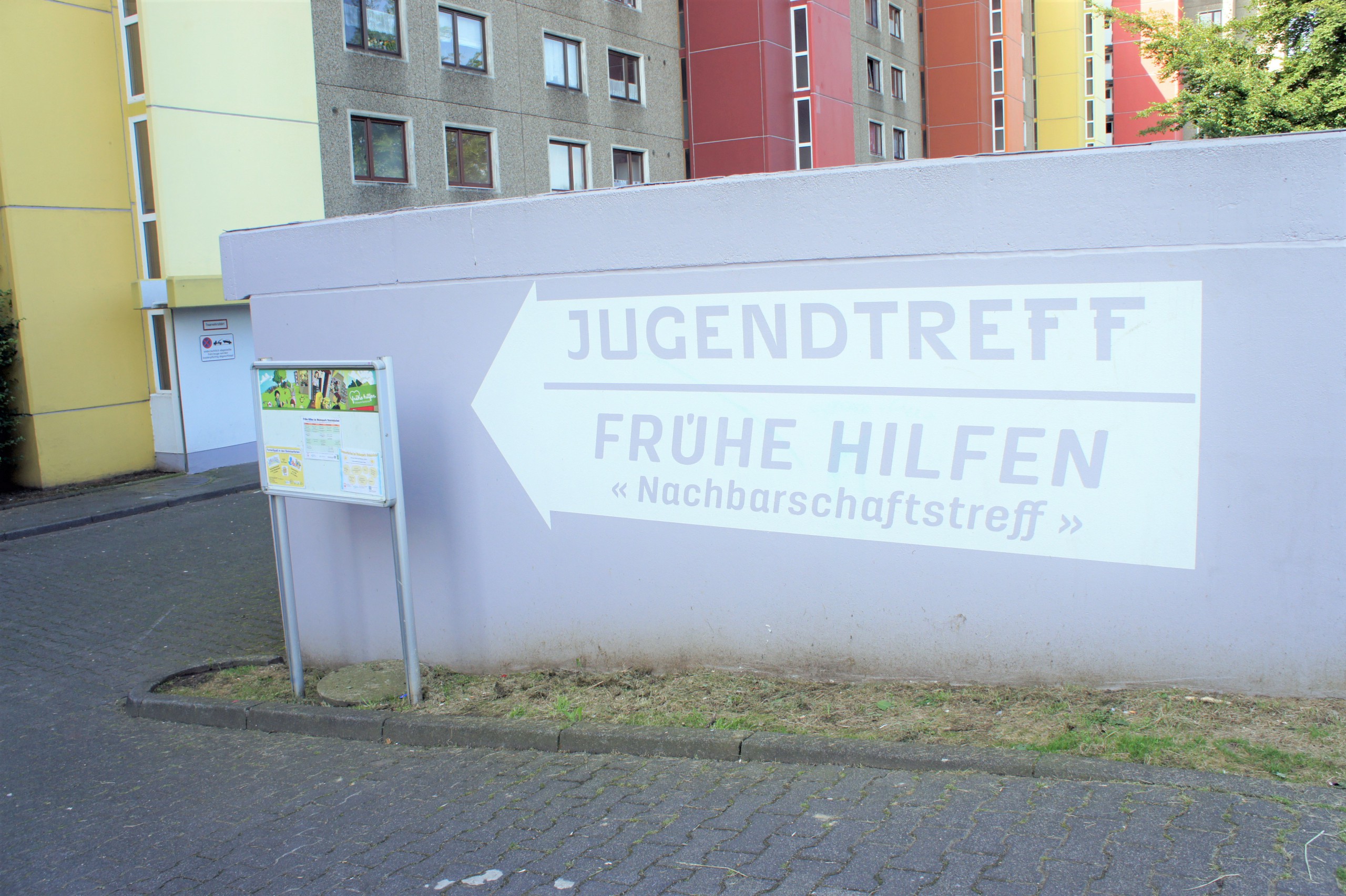 Auf eine Betonwand gemalter Hinweis zu den Frühen Hilfen und dem Jugendtreff