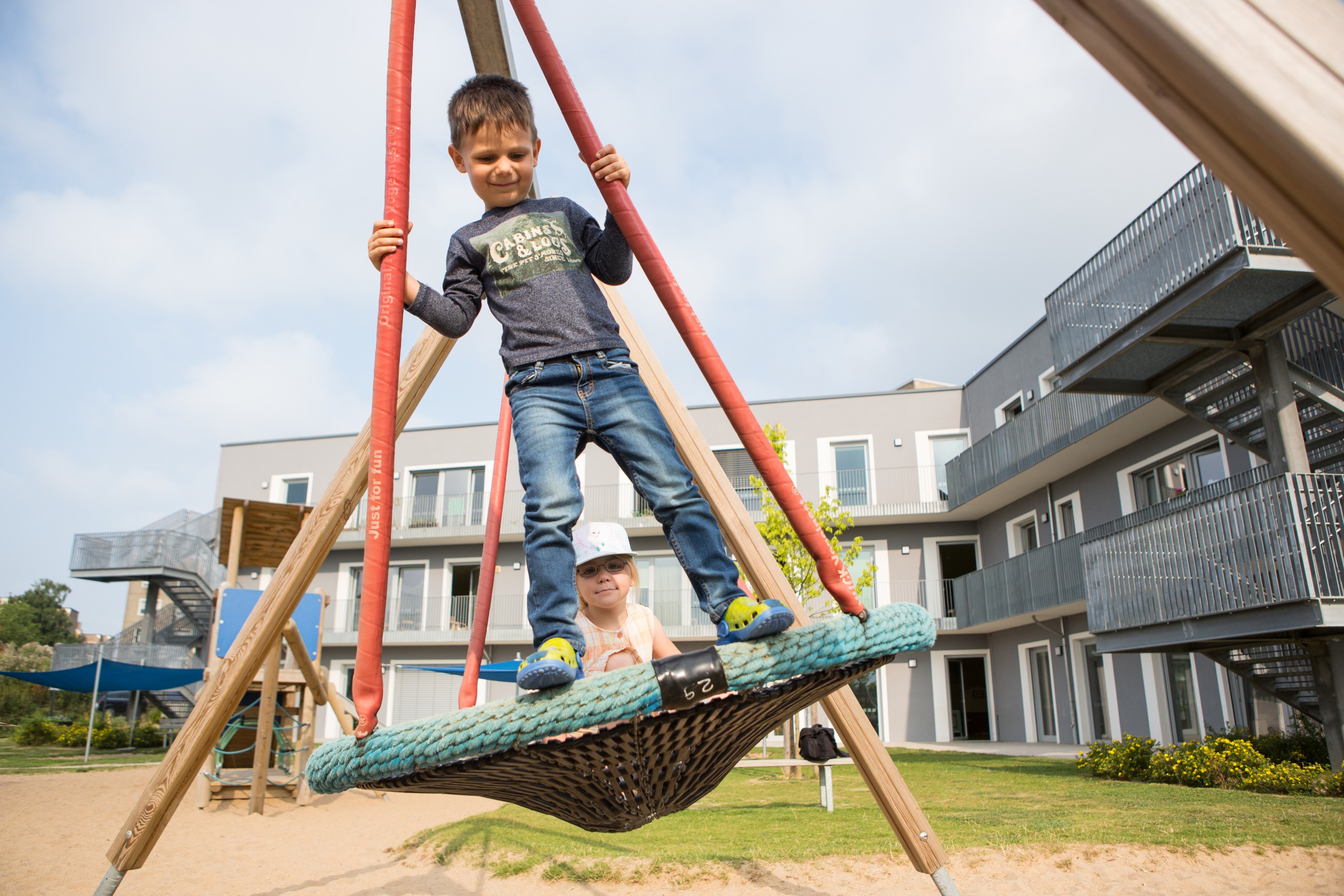 Zwei ältere Kinder schaukeln auf einer Nestschaukel