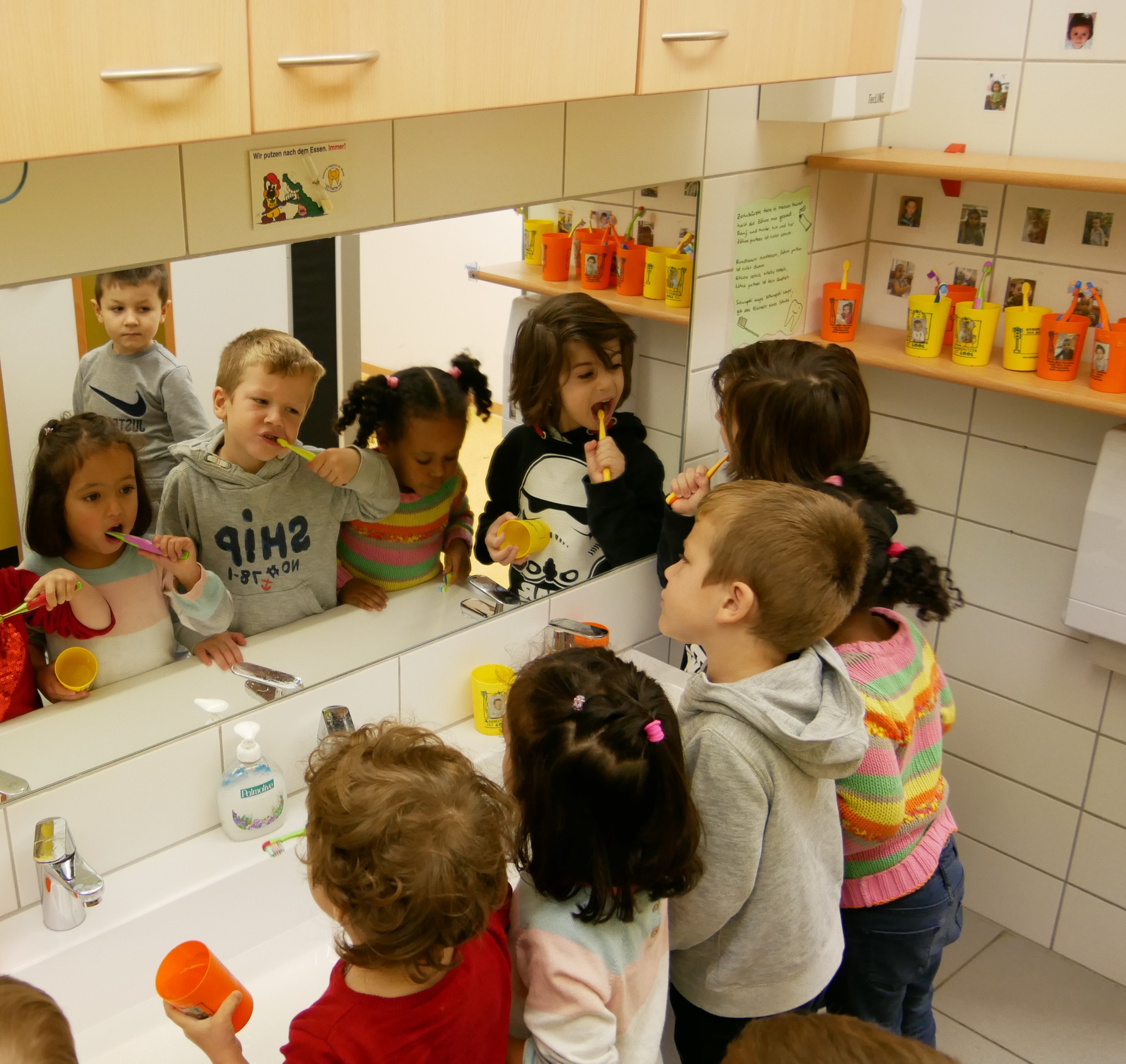 Kinder putzen sich die Zähne an einem langen Waschbecken