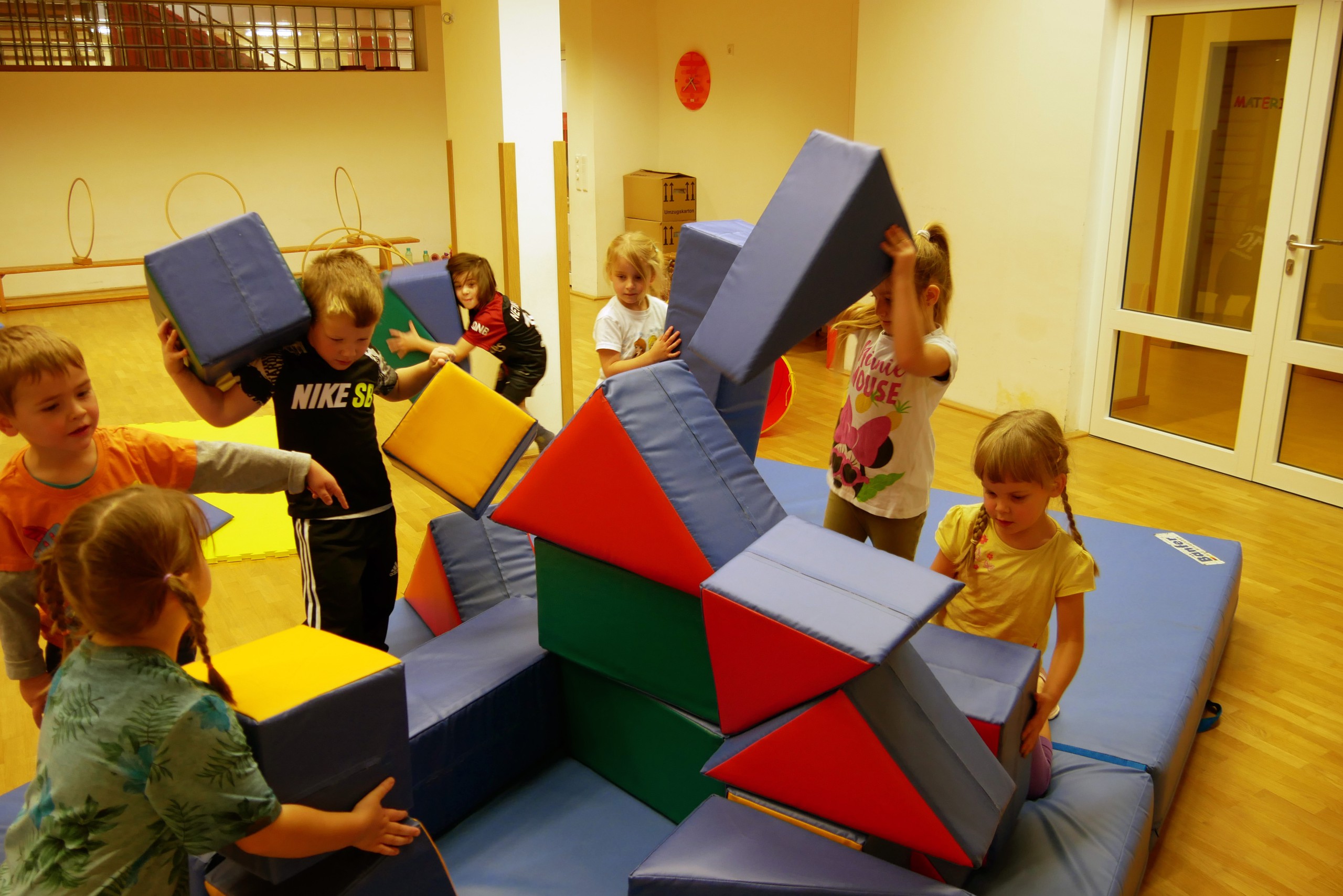 Kinder spielen und bauen in der Turnhalle mit großen Schaumstoffelementen