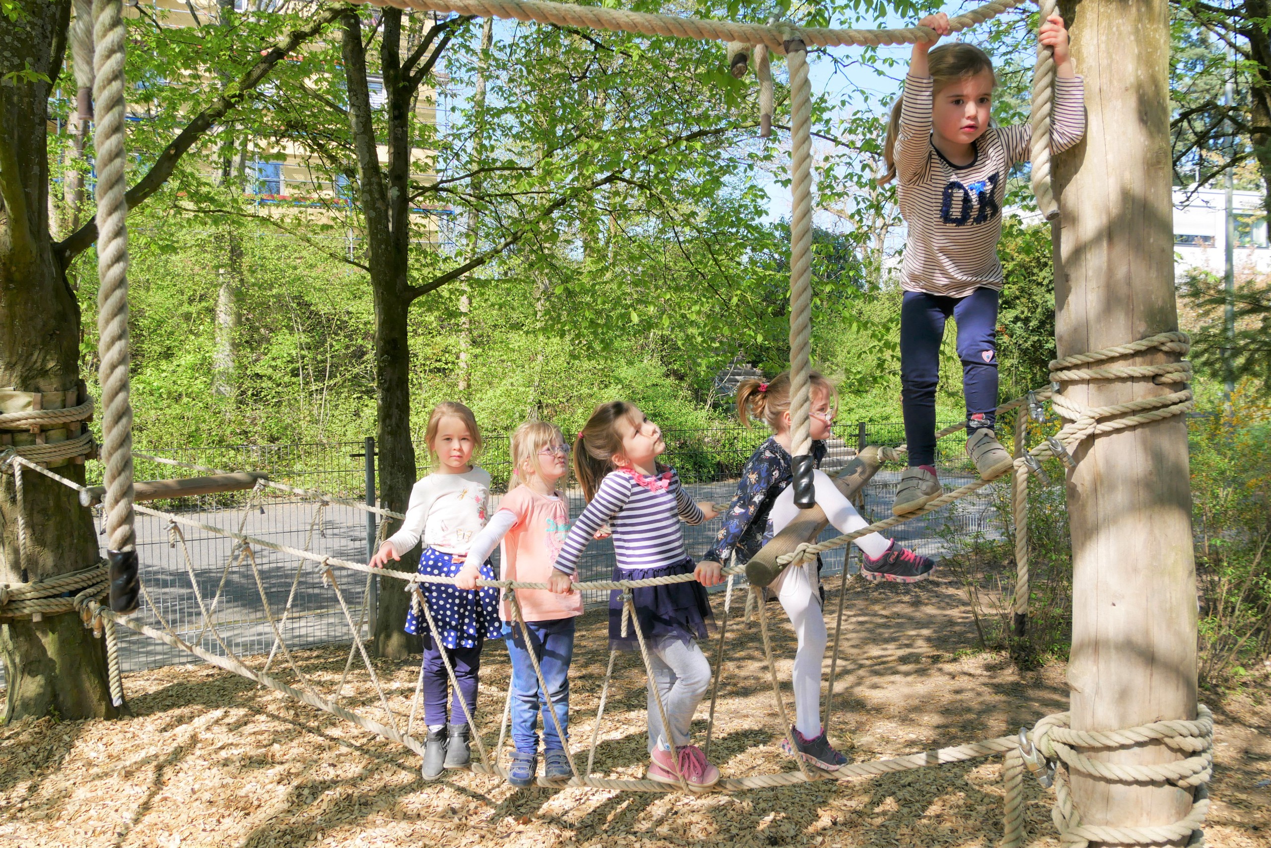 Kinder klettern auf dem Außengelände auf einer Seillandschaft