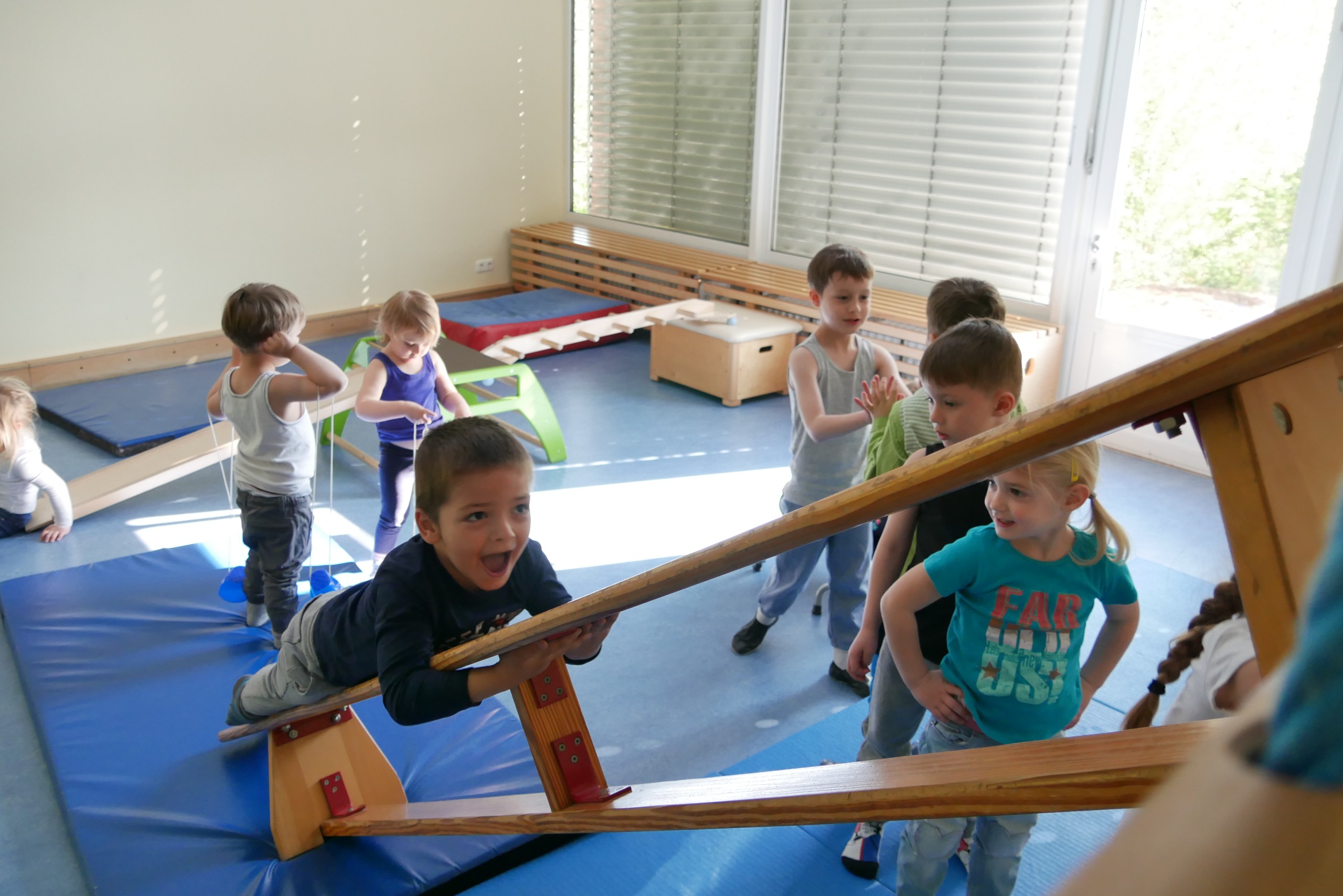 Kinder spielen in der Turnhalle auf einer aufgebauten Bewegungslandschaft