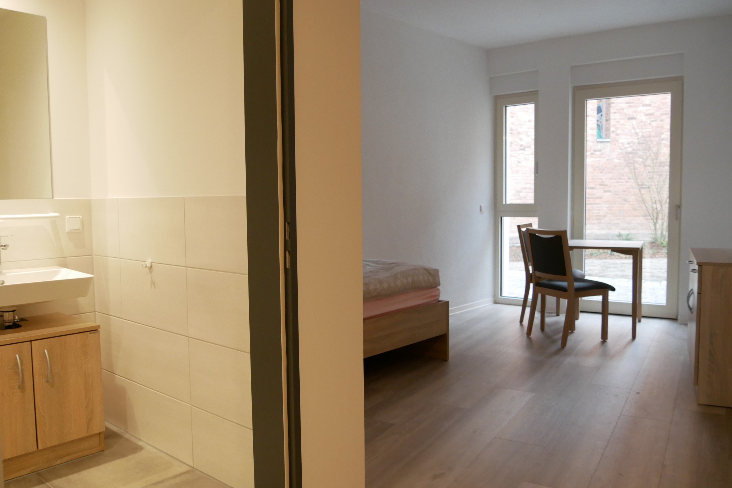 Ein Zimmer mit Bad, Bett, Kommode, Tisch und Stuhl möbliert