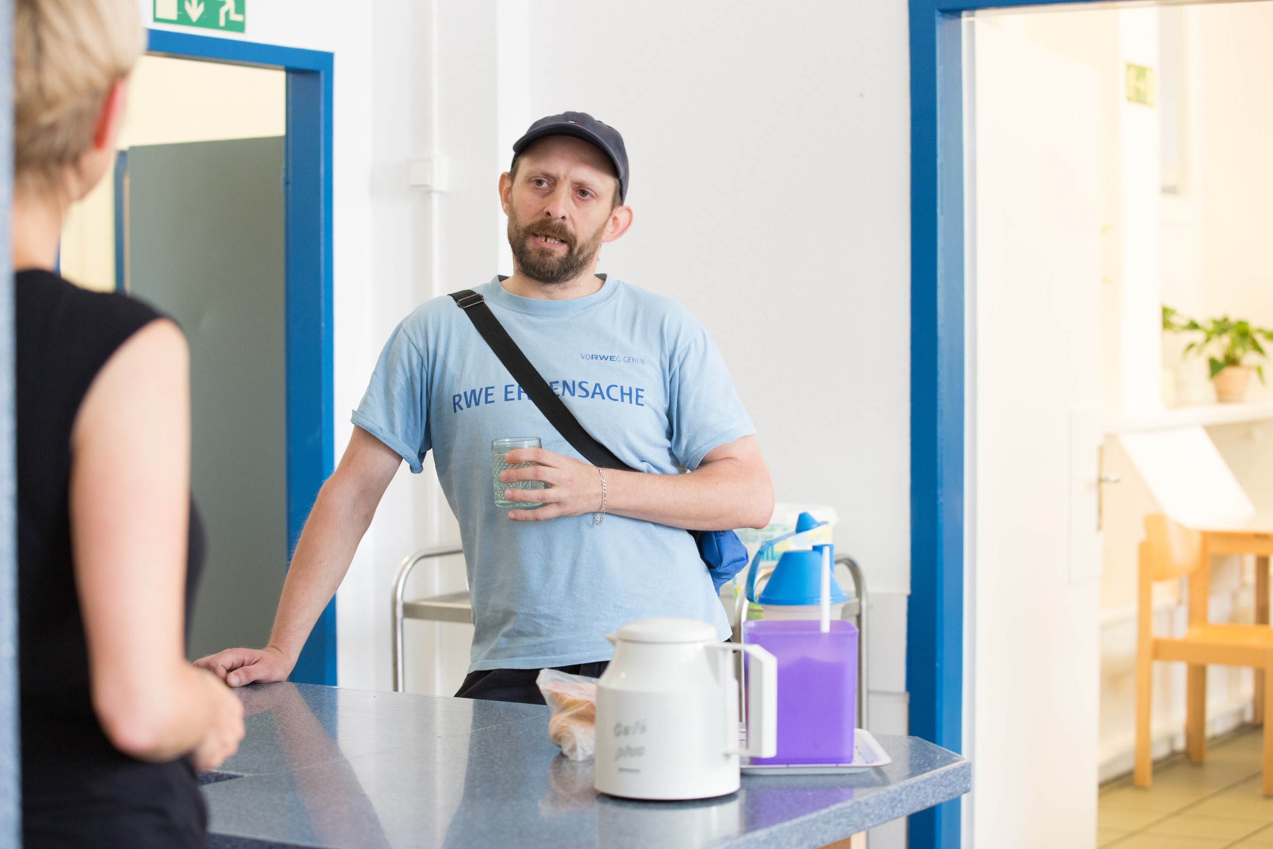 Zwei Personen im Gespräch an einer Theke mit Kaffee und Mineralwasser